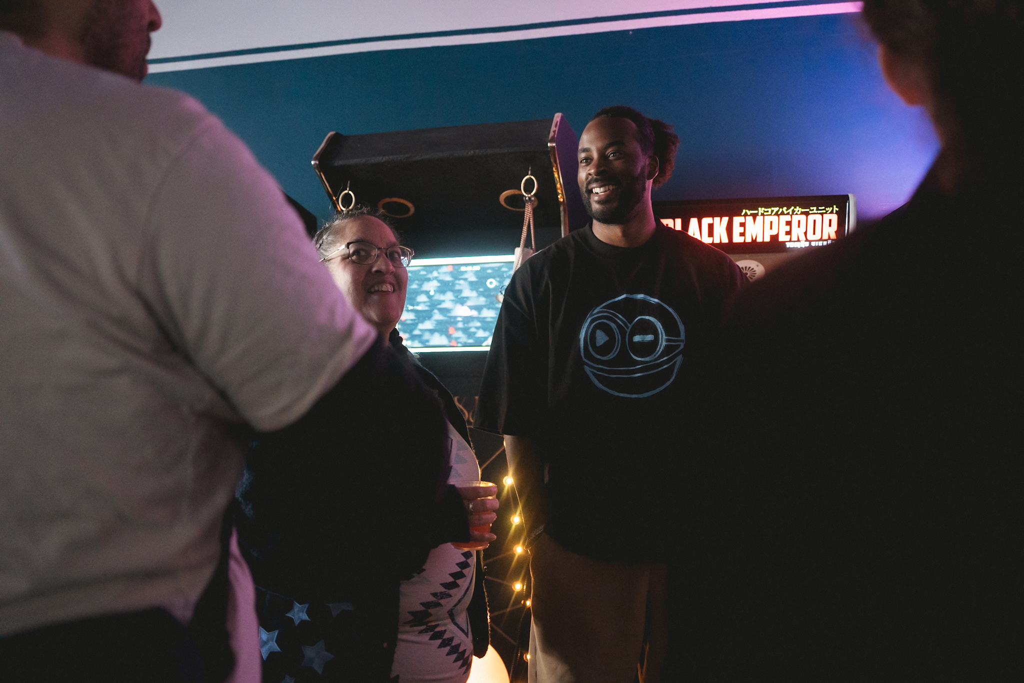 Ryan The Son at an arcade listening event in the A Time to Feel tee, smiling at fans